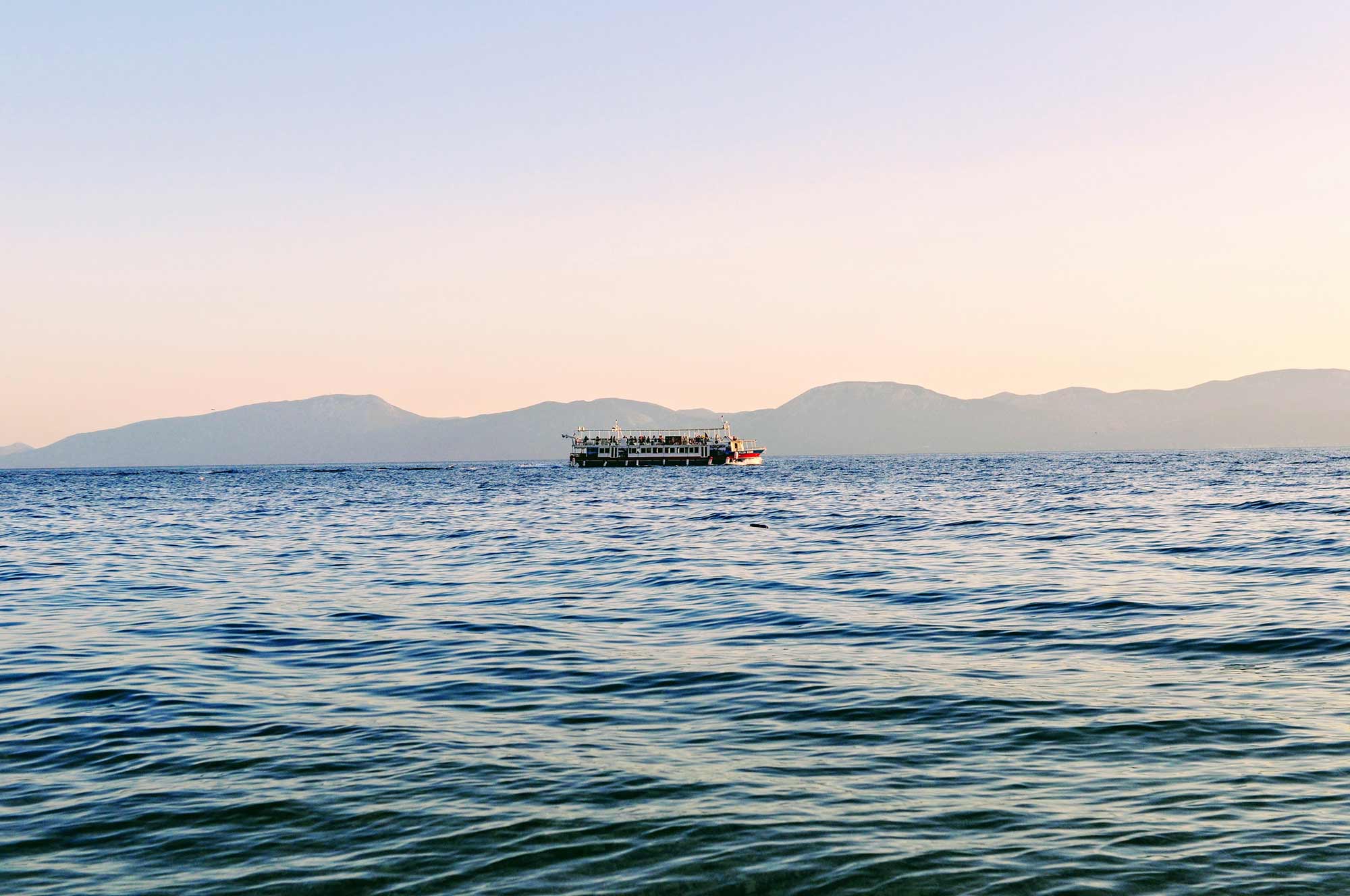 Das Bild zeigt ein Schiff, das vor der Makarska Riviera durch das Wasser der Adria fährt